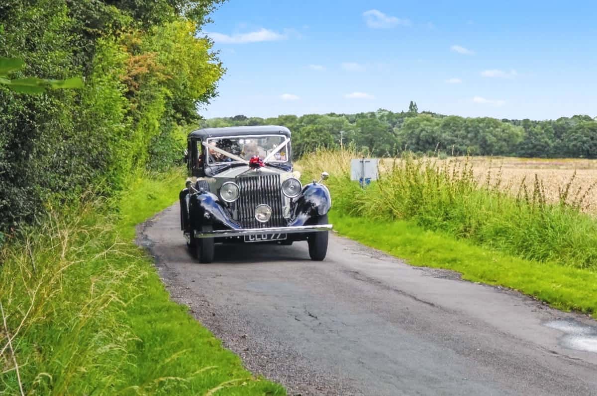 Vintage car arriving at wedding venue.
