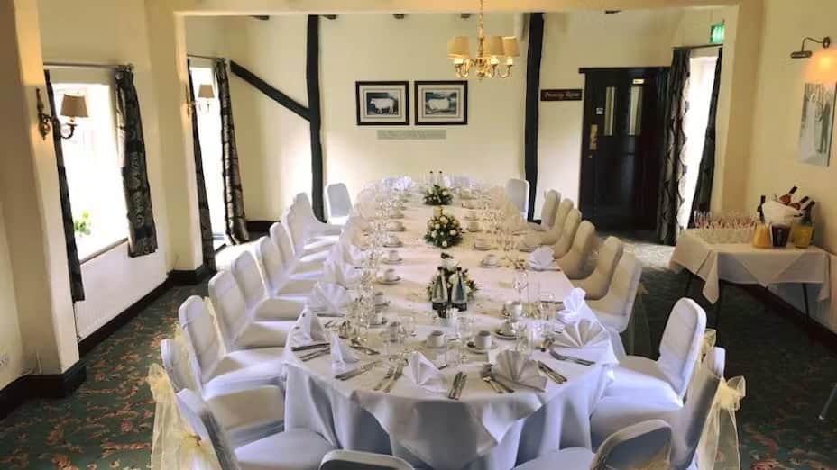 Beautifully decorated wedding dining room with a long table, white linens, and floral centerpieces.