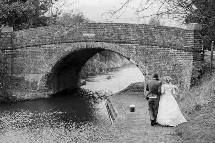Bride and groom walking under a historic brick bridge at Marston Farm Hotel.